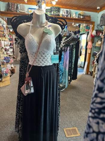 mannequin with a coordinated ensemble of a  white crochet top and black skirt and travel purse