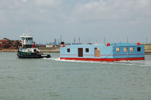 Original Harrisons Landing floating barge being driven by a barge to location