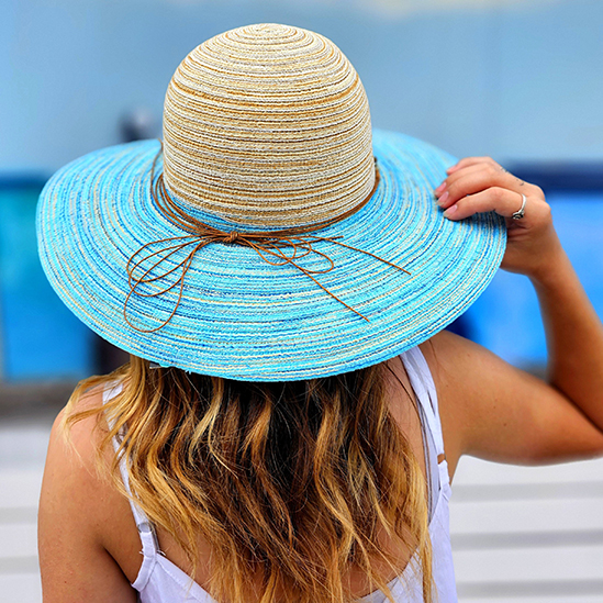 Young lady with a fun colorful beach hat looking into the Corpus Christi Bay
