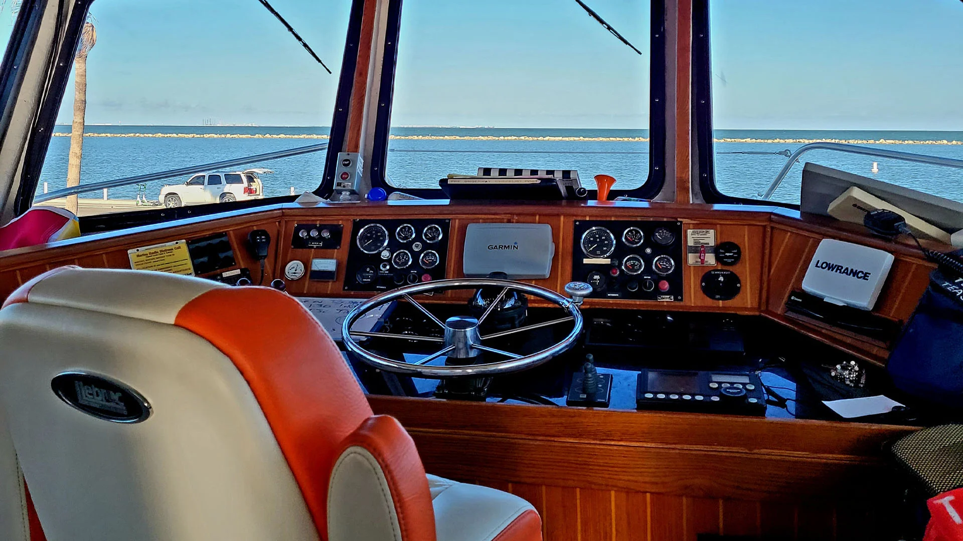 Texas Tease Boat cockpit with steering wheel and navigation equipment overlooking a calm blue sea under clear sky